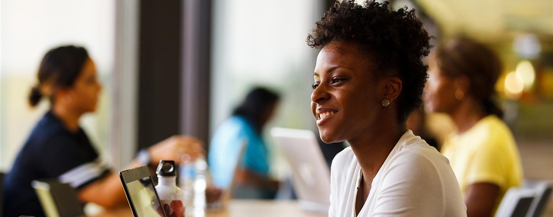 Picture of a woman smiling as she video conferences on a laptop.