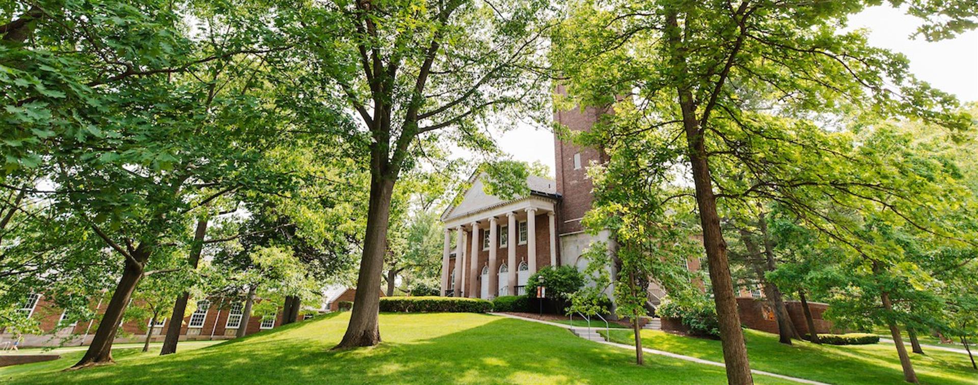 Photo of a brick building at Kalamazoo college surrounded by green trees