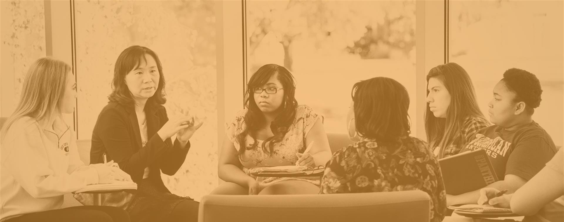 A picture of a group of students sitting with their professor and talking