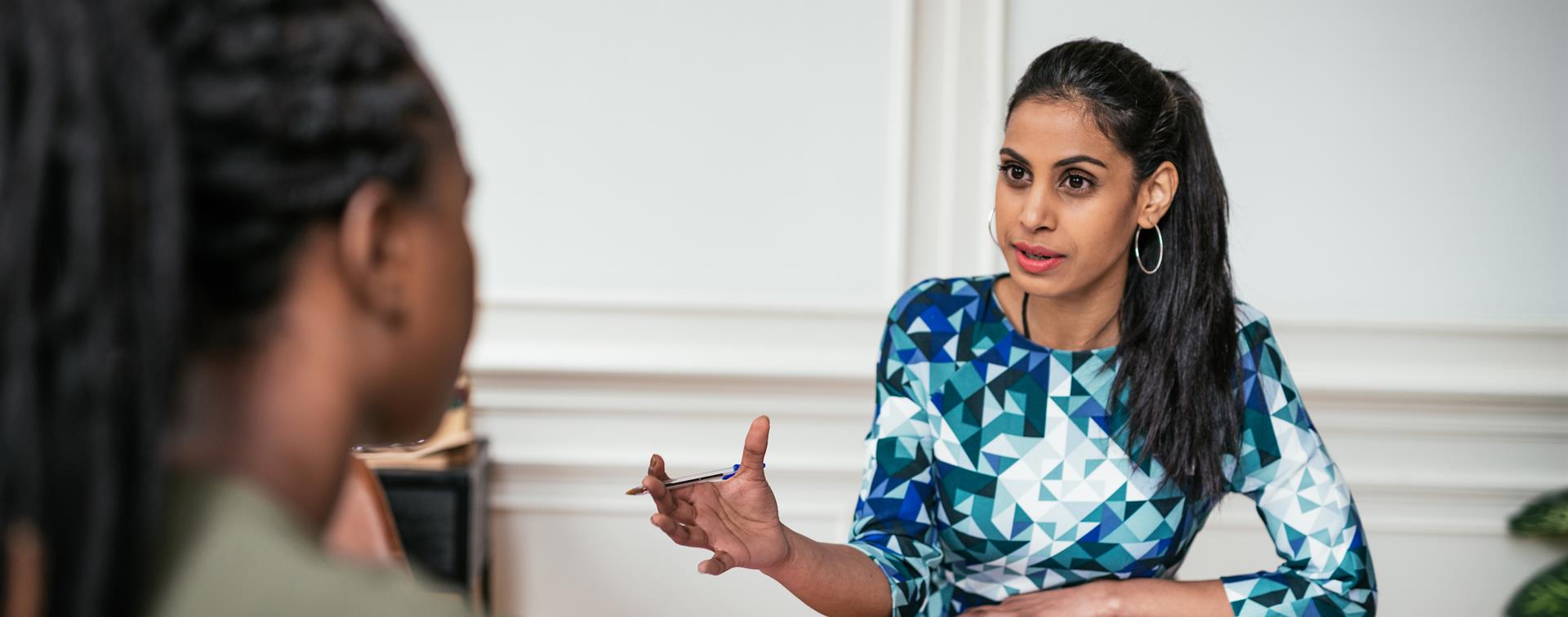 Photo of female faculty member in discussion with student across a desk