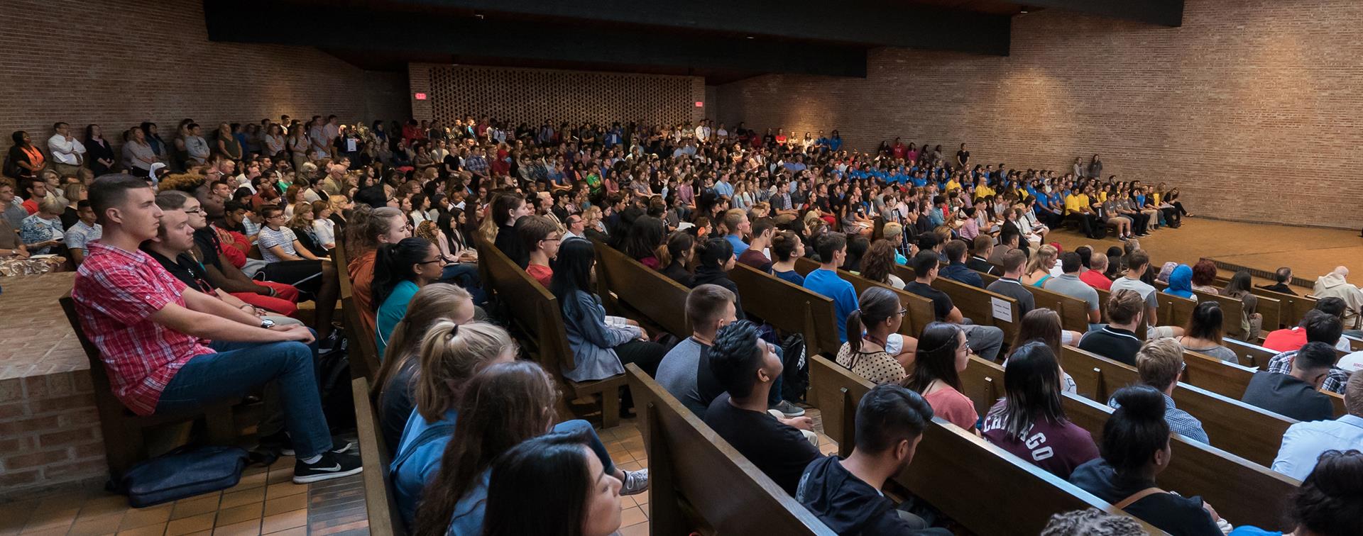 Students sit in a large conference hall.